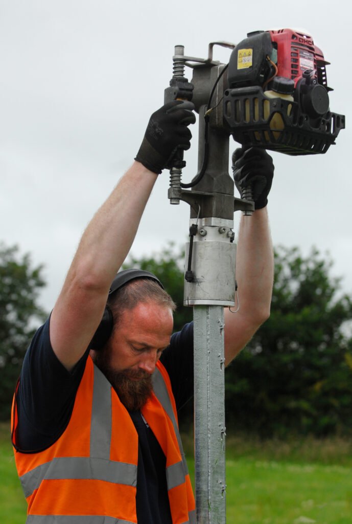 Trabajador instalando un poste con una clavadora motorizada Iberfence. Herramienta diseñada para eficiencia y precisión en la instalación de cercas.