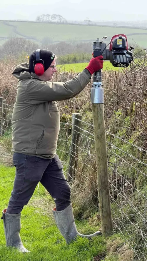 Pfahlramme IBF-107 mit rundem 107-mm-Adapter beim Einschlagen eines Holzpfahls in einen Weidezaun